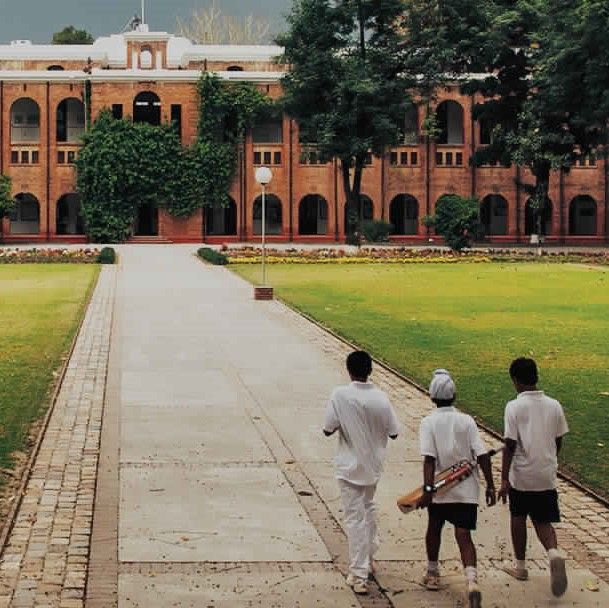 Three students of the Doon School walk towards the building with a cricket bat in hand